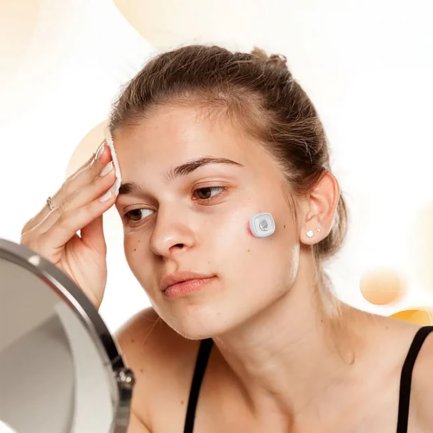 A woman applied a Viva Glam acne light therapy patch to her face with a mirror